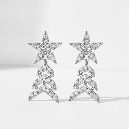 A pair of silver-toned drop earrings featuring a star-shaped top pavé set with clear stones, connected to a chevron-patterned dangling section also paved with clear stones, shown on a light gray background.