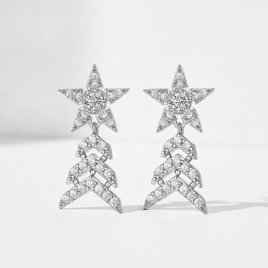 A pair of silver-toned drop earrings featuring a star-shaped top pavé set with clear stones, connected to a chevron-patterned dangling section also paved with clear stones, shown on a light gray background.
