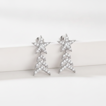 A pair of silver-toned dangle earrings featuring a star-shaped top set with clear crystals and a dangling chevron tree design below, displayed on a clean white surface.